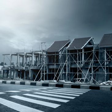 Partially constructed buildings under a cloudy sky near a crosswalk.