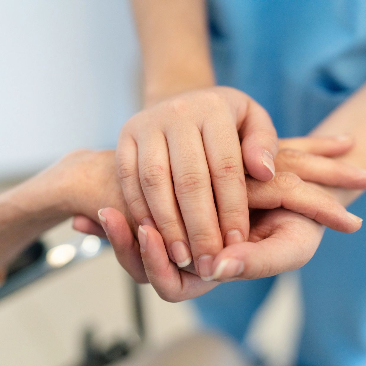 Nurse comforting a patient by holding their hands gently.