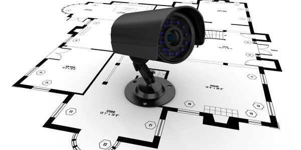A security camera on top of a house floor plan blueprint.