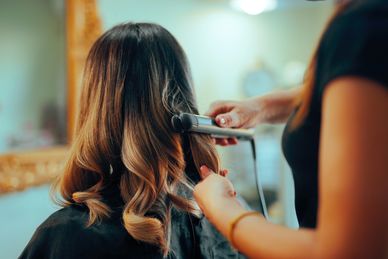 A person getting their hair styled with a curling iron.