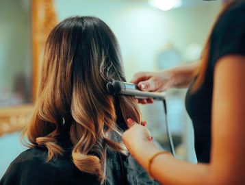 Woman having her hair styled with a curling iron.