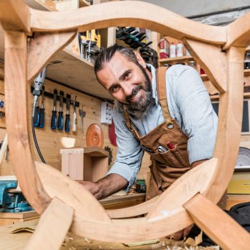 Carpenter working on a wooden frame in a workshop.