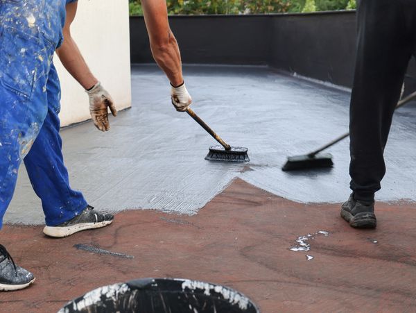 Two people applying concrete coating to a floor