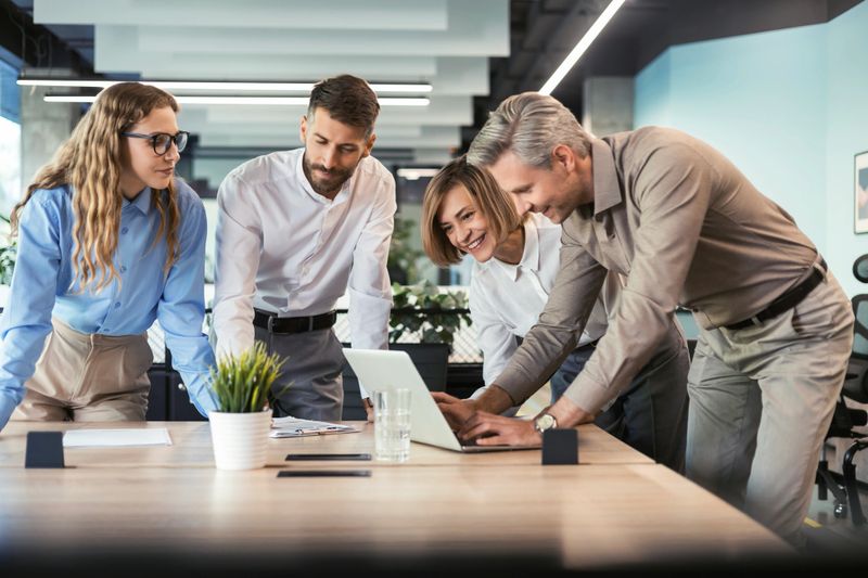 Group of young modern people in formalwear using modern technologies while working in the creative office.