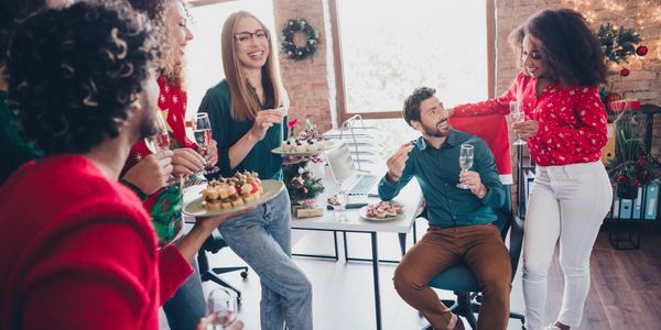 Colleagues enjoying a festive office party with drinks and snacks.