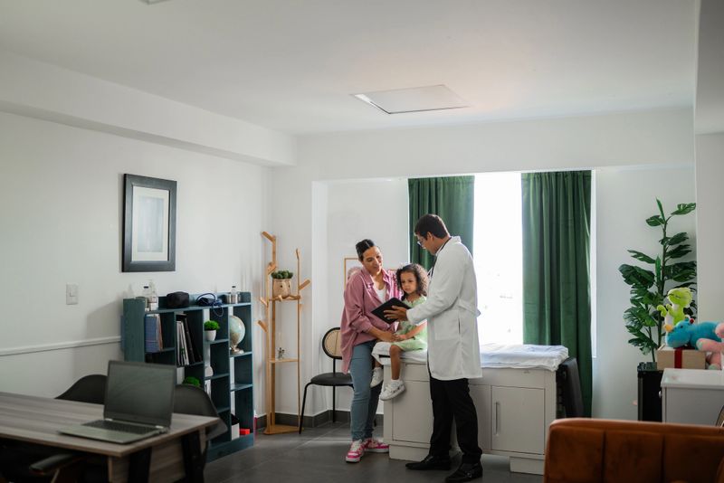 Doctor showing tablet to mother and daughter during consultation at hospital