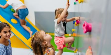 Children enjoying indoor climbing and play activities together.