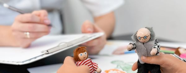 Therapist showing child happy/sad picture siting on floor