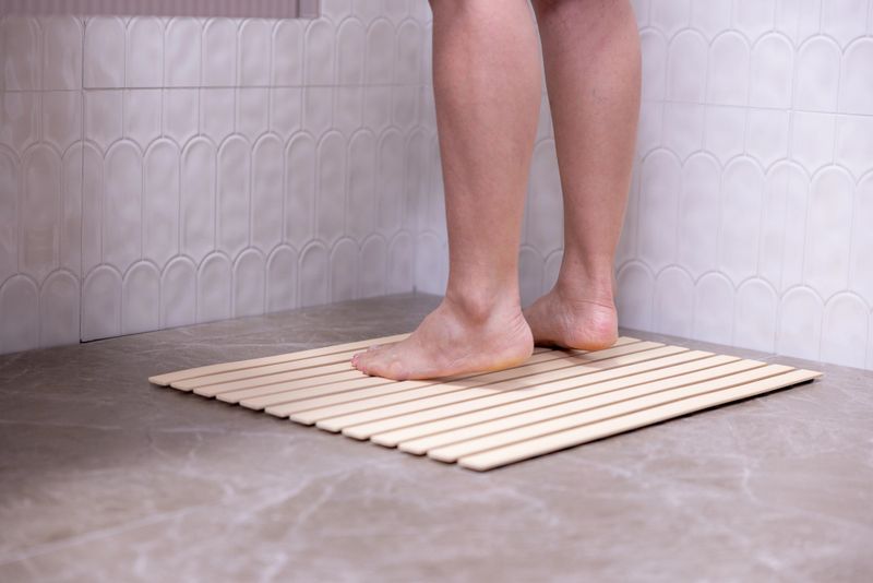 A woman's legs standing in the shower in the bathroom on a non-slip mat.