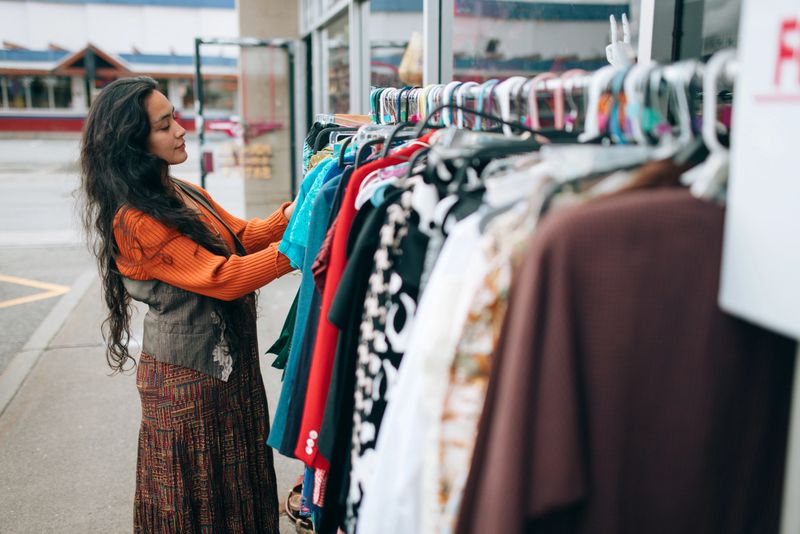 An Indigenous Alaskan woman shops in a fun fashion thrift shop, trying on clothing and hats and putting together outfits.  Shot in Anchorage, Alaska.