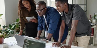 Three people collaborating on a project using a laptop.