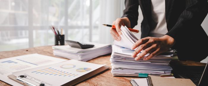 Person organizing a large stack of financial documents at a desk.