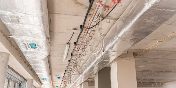 Exposed ceiling with insulation and wiring in a building under construction.