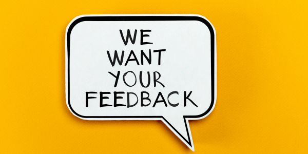 Speech bubble with 'We Want Your Feedback' on a yellow background.