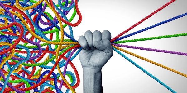 A fist untangling colorful ropes from a chaotic mess to order.