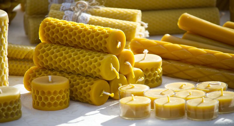 A collection of handmade beeswax candles in diverse forms, showcasing the intricate honeycomb texture and vibrant yellow hue, perfect for sustainable home decor and ambient lighting.