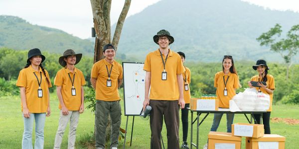 A group of volunteers in yellow shirts standing outdoors with donation boxes and supplies.