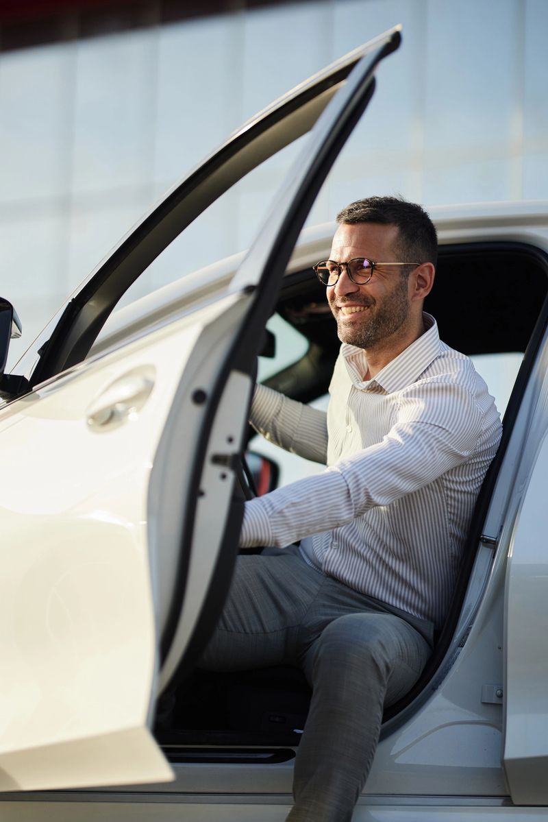 Happy male entrepreneur opening the door before exiting the car on the street.