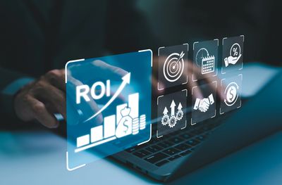 Digital interface showing ROI growth with business icons over a laptop keyboard.