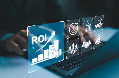 Digital interface showing ROI growth and financial icons above a laptop keyboard.
