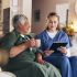 Caregiver and elderly woman sharing a joyful moment on the couch.