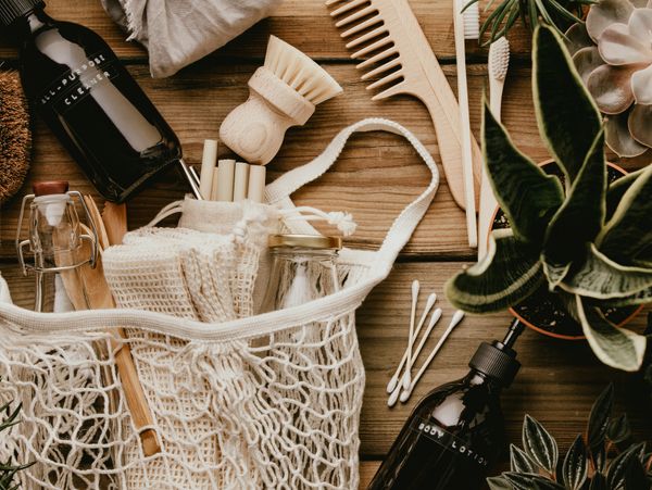 Eco-friendly personal care and cleaning items with plants on a wooden surface.