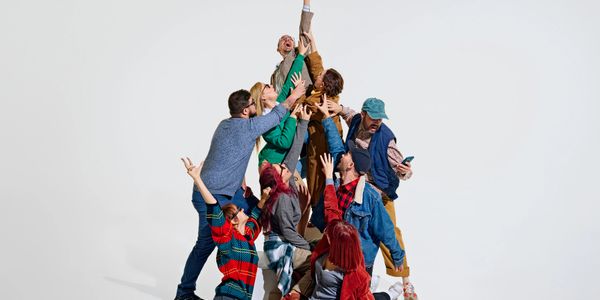 Group of people reaching upward together.