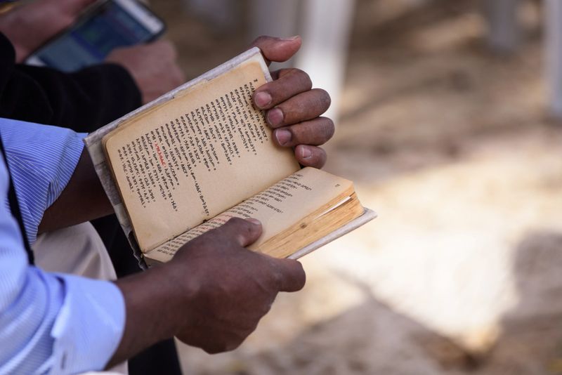 Closeup of a member of the Beta Israel Jewish community reading from a siddur or prayer book in Amharic during the Festival of Sigd in Jerusalem, Israel.