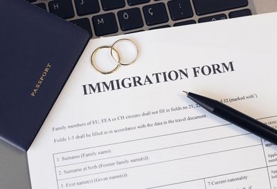 Immigration form with passport, rings, and pen.