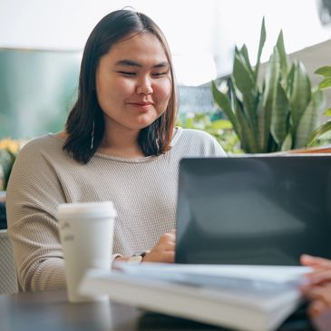 Young woman working on a laptop with a coffee cup nearby.