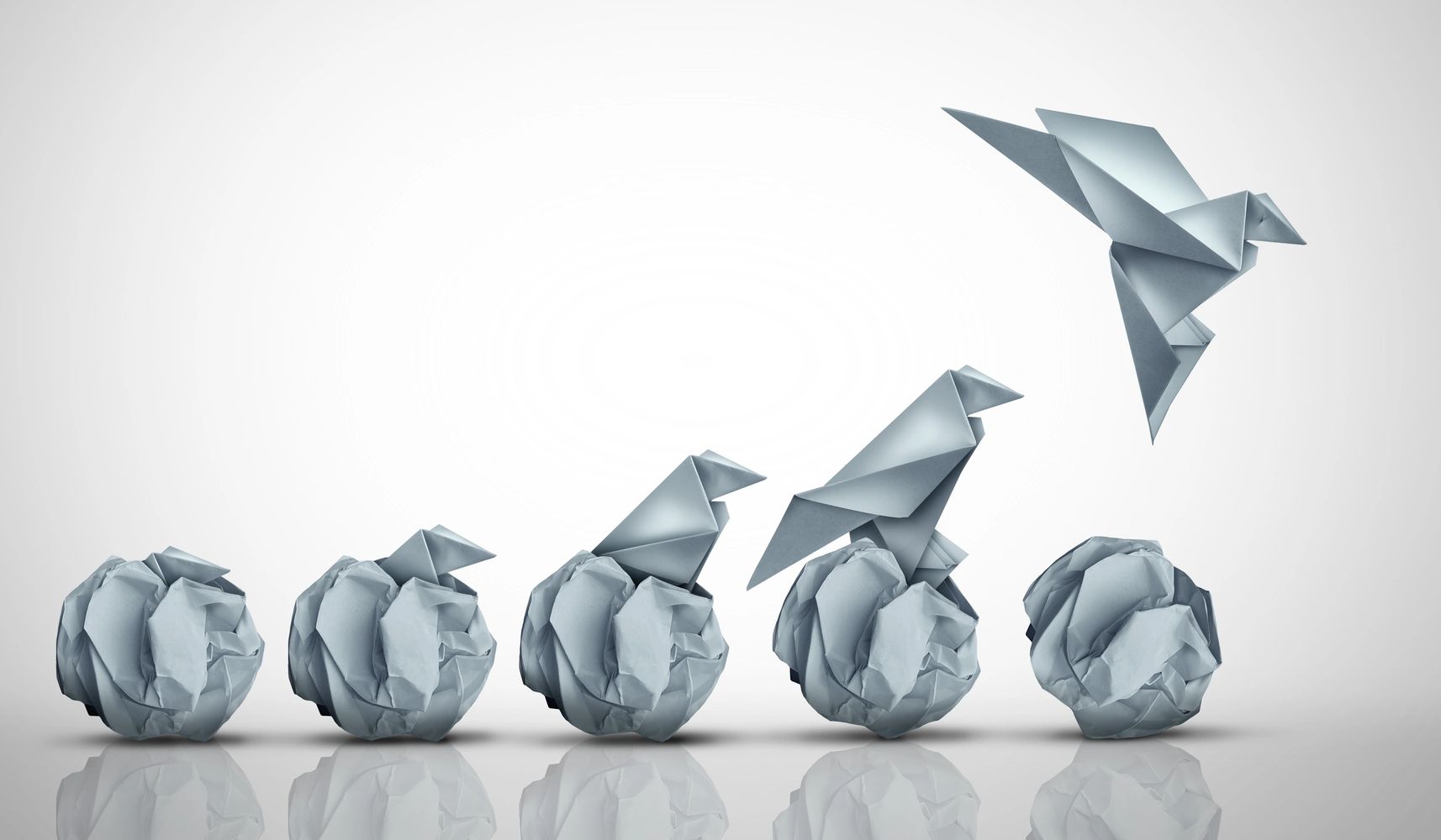 Origami birds emerging from crumpled paper balls, symbolizing growth and transformation.