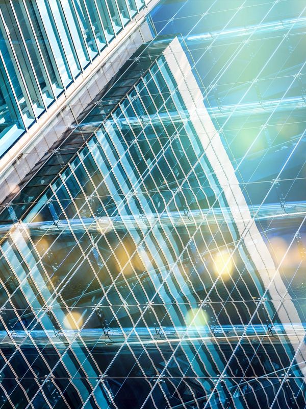 Modern glass skyscraper reflecting light with geometric patterns.