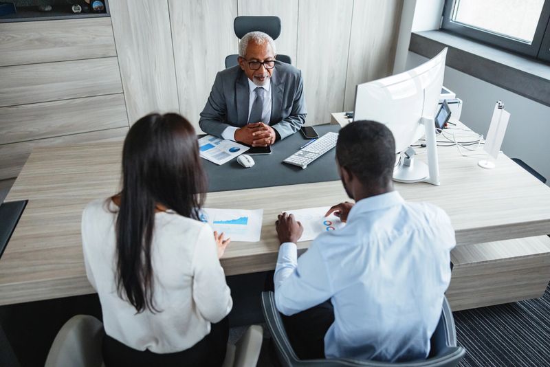 Top view of Black, Latin, and mixed race business professionals engaged in a corporate meeting. Diverse group collaborates in a modern office setting, conveying concepts of teamwork, strategy, and success.