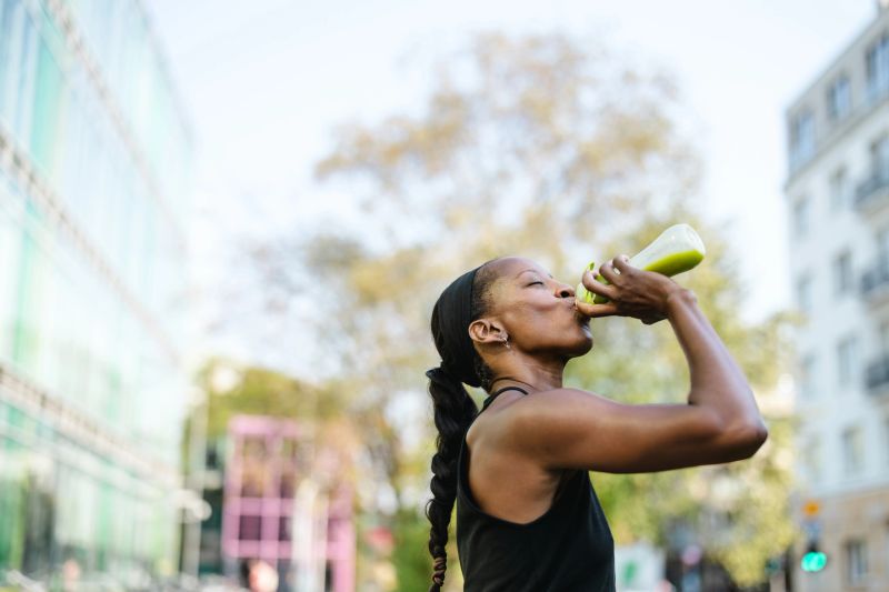 Woman drinking green smoothie after fitness running workout
