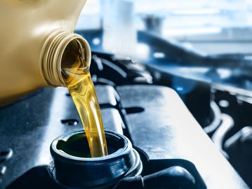 Pouring golden motor oil into a car engine.