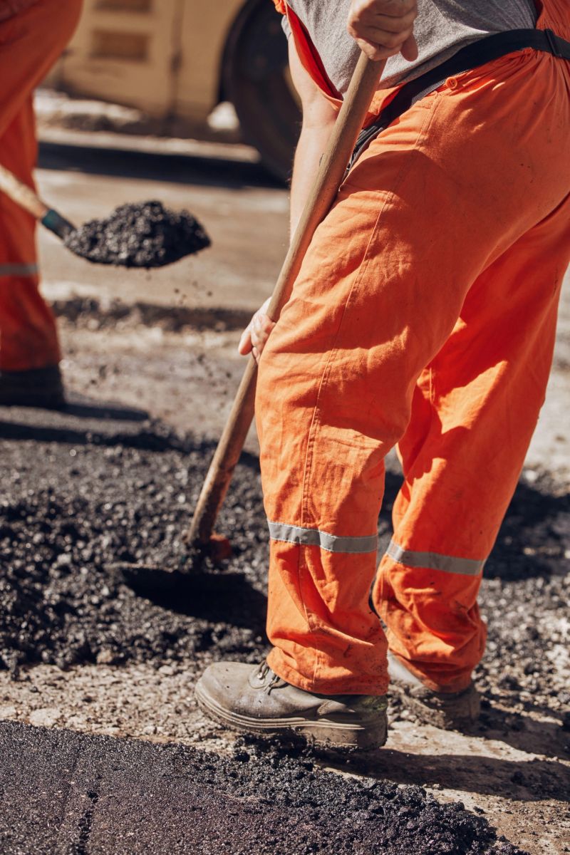 Construction workers working on a new asphalt layer on a public street.