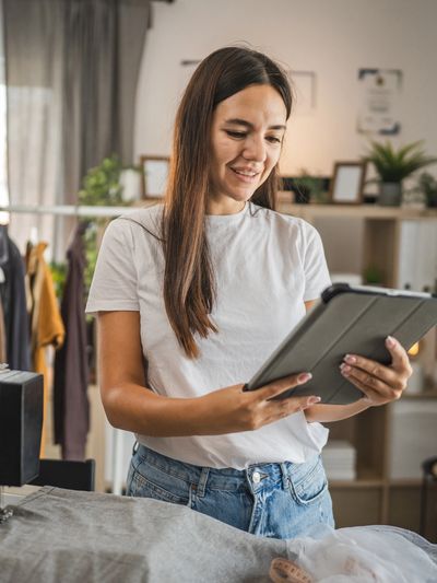 Young woman using a tablet in a cozy sewing room.