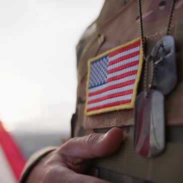 Close-up of a soldier's uniform with a US flag patch and dog tags.