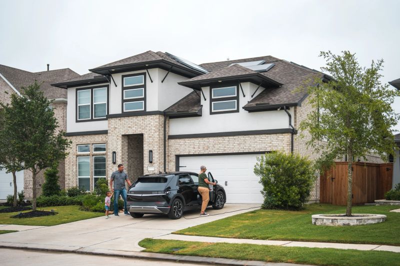 A diverse family unloads groceries from their electric car outside a modern solar-paneled home, reflecting a sustainable living environment.