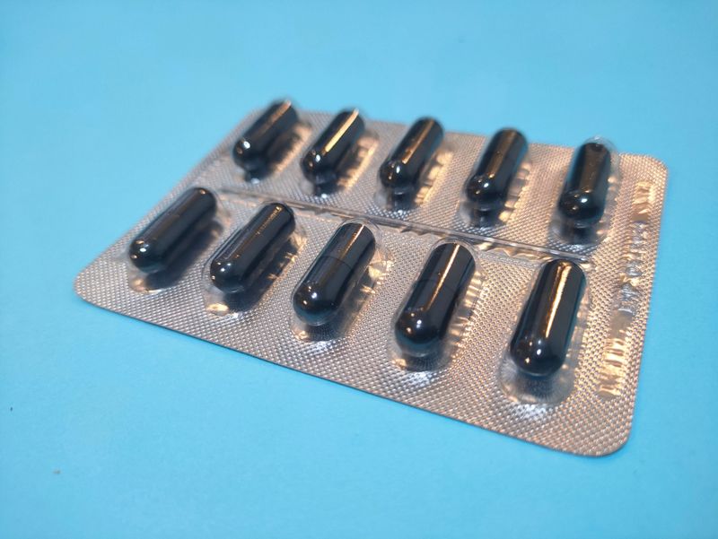 Capsules and vitamins in blister packs on blue background with copy space