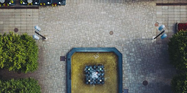 Aerial view of a square with a central fountain and surrounding greenery.