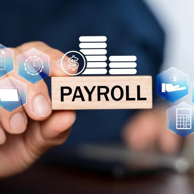 Hand holding a block with the word Payroll and financial icons.