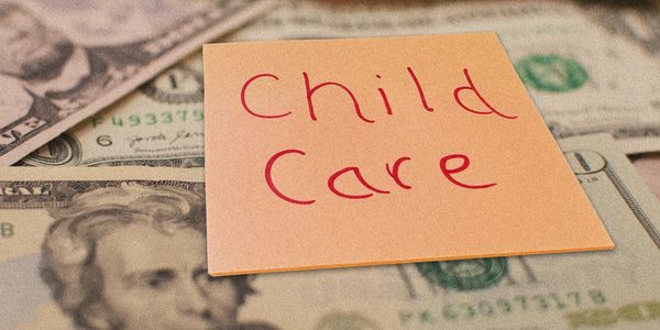 Sticky note with "Child Care" on US dollar bills.