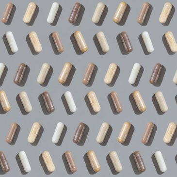 Pattern of assorted capsules in various shades on a gray background.