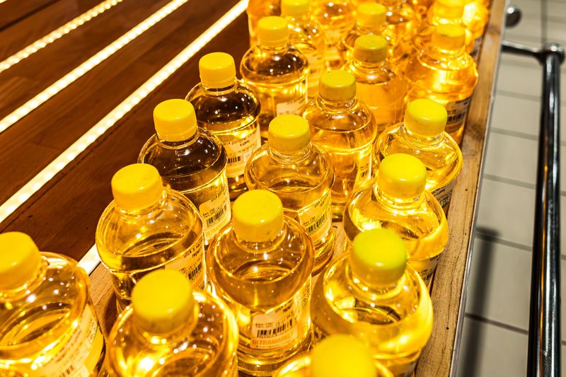 A shelf with bottles of vegetable oil of golden color. Sunflower or olive oil. Plastic container. Shelf in the store. Healthy food. A healthy lifestyle.