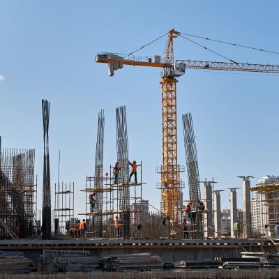 Construction workers on a building site with a large crane.