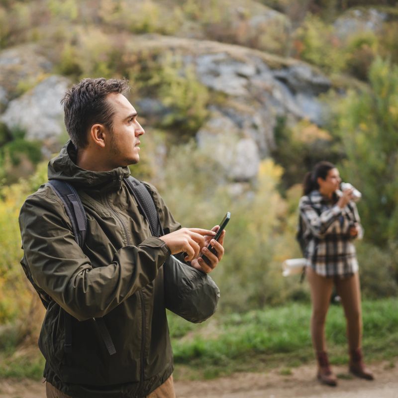 Adult man hiker look for path and directions on mobile phone