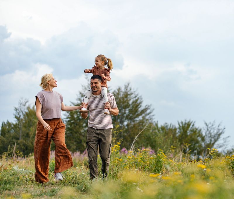 A joyful family enjoying a walk in the countryside, surrounded by lush greenery and wildflowers, embodying happiness and togetherness in nature.