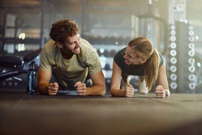 Two people doing plank exercises together in a gym.