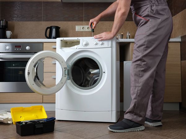 Technician repairing front loading laundry washer. 